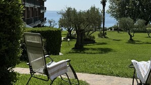A patio area with two lounge chairs, a building with a balcony, and a view of the sea. - Stupenda Vista Lago, Appartamento con Piscina (Solarolo)