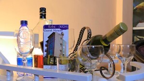 Un carrito de bar con varias botellas y copas, incluyendo una botella con la etiqueta 'Keba (KGH)'.