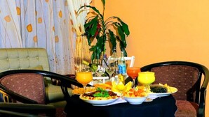 Una mesa de comedor lista con varios platos, bebidas y una planta al fondo.