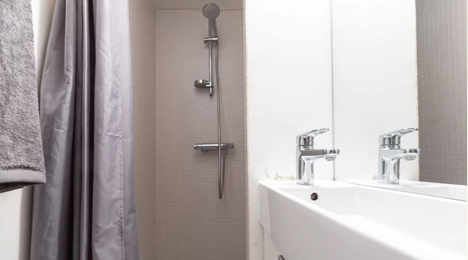 Un baño moderno con ducha, lavabo y espejo.