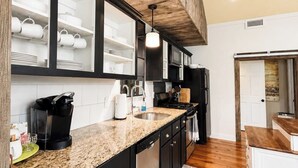 A kitchen with a granite countertop, black cabinets, and a wooden ceiling.