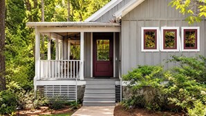 A house with a porch, a red door, and a small garden.