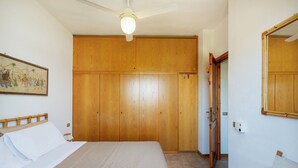 A bedroom with a bed, wooden wardrobe, and a ceiling fan. - Casa Rosella by Wonderful Italy (Olbia)