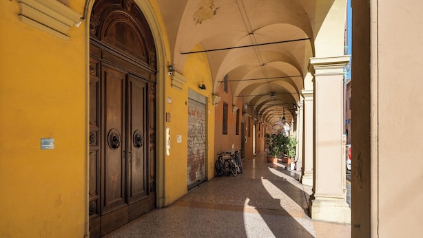 Un corridoio con parete gialla, porte in legno e pavimento piastrellato.