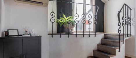 A corner room with a staircase, a black cabinet, and a potted plant.