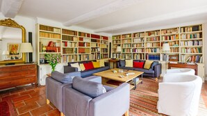 Ein geräumiges Wohnzimmer mit einer großen Bücherwand, einem Sofa, einem Couchtisch und einem gemusterten Teppich.