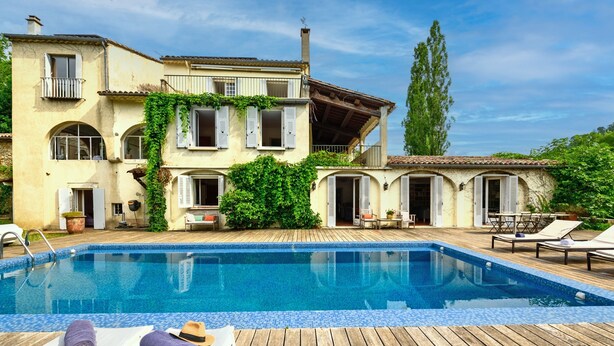 Ein Poolbereich mit Liegestühlen und einer Holzterrasse.