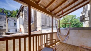 A wooden deck with a hammock, a wooden chair, and a view of old stone buildings.