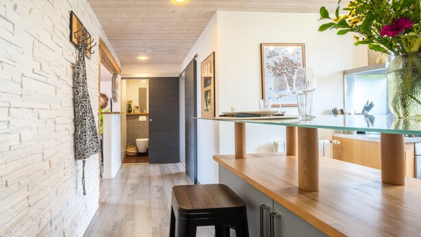 Una cocina moderna con encimera de madera, salpicadero de vidrio y un taburete negro.
