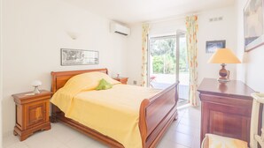 Una camera da letto con un letto di legno, un comodino, una lampada e vista sull'esterno da una finestra.
