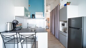 Une cuisine de taille réduite dotée d’un îlot central, d’un réfrigérateur et d’un four à micro-ondes.