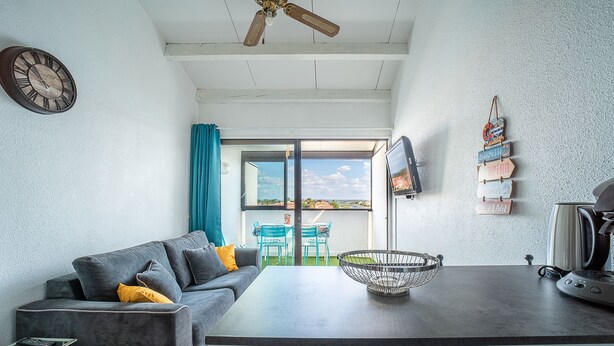 Un espace de vie moderne comprenant un canapé, une table à manger, une bouilloire et une vue sur l’extérieur.