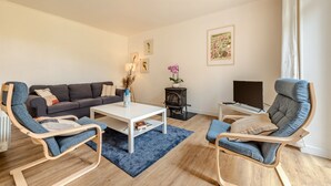 Una sala de estar con sofá, dos sillones, una mesa de centro, chimenea y televisor.