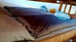 A bunk bed with a wooden headboard, a pillow, and a rolled-up blanket.