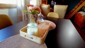 A dining table with a vase of flowers, a glass jar, and salt and pepper shakers.
