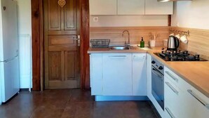 A kitchen with white cabinets, a wooden door, a gas stove, and a sink.