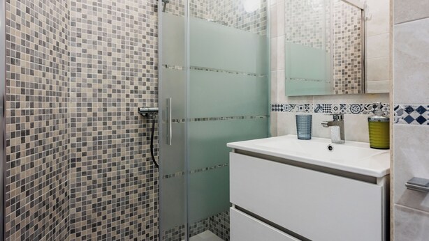 A bathroom with a glass-enclosed shower, tiled walls, a white sink, and a mirror above it. - Il giardino di Aci by Wonderful Italy (Catania)