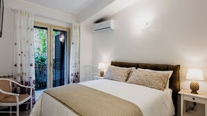 A bedroom with a bed, two bedside tables with lamps, a chair, and a window with curtains. - Il giardino di Aci by Wonderful Italy (Catania)