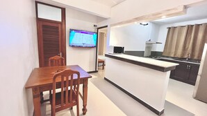 A compact kitchen with a dining area, a microwave, and a TV displaying a sports game. - Modern apartment for rent in La Gaulette.
Suitable for couple or family. (La Gaulette)
