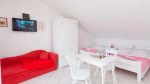 A white room with a red sofa, a white table, and a white bed. - Apartments Lili (Podgora)