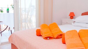 A hotel room with a bed, a nightstand with a lamp, and a view of the outside through a sliding door. - Apartments Lili (Podgora)