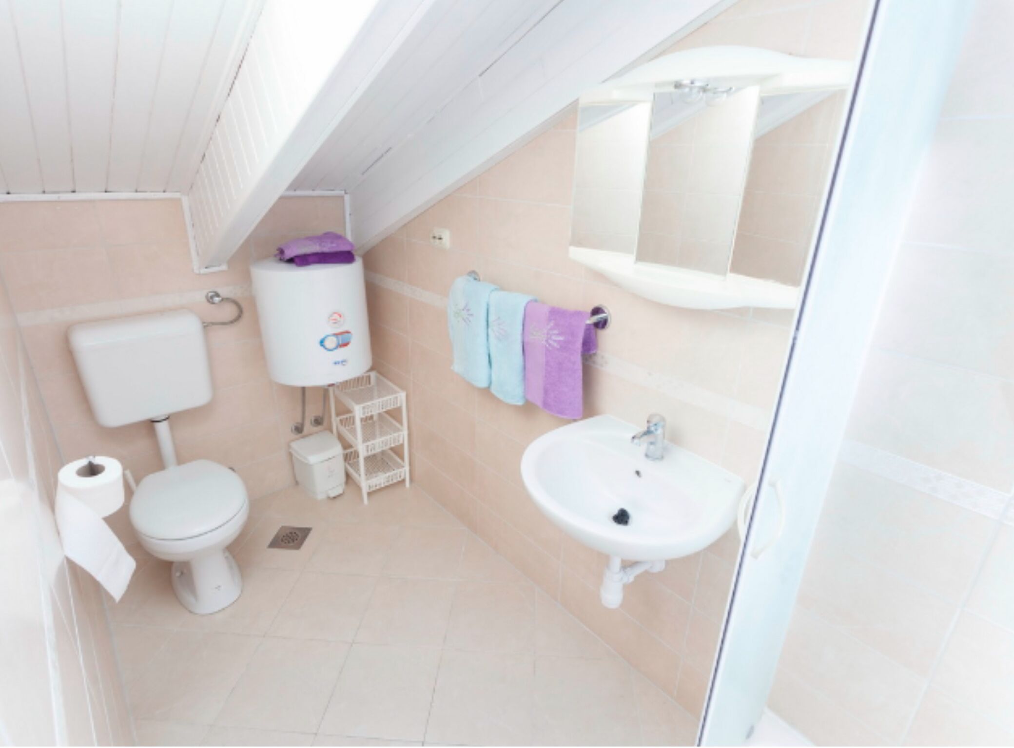 A small, bright bathroom with a toilet, sink, and a white pedestal tank.