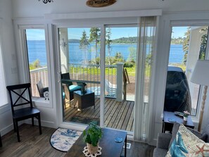 Una habitación con vista a un lago, una terraza con mobiliario exterior y un cartel que dice 'WELCOME'.