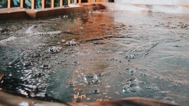 Une terrasse en bois avec un jacuzzi, des rampes en bois et un banc.