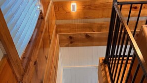 Un escalier en bois avec une rampe en métal, menant à l’étage supérieur.