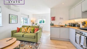 Eine moderne Küche mit Backofen und Essbereich, ausgestattet mit einem grünen Sofa und einem Holztisch.
