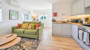 A modern kitchen with a built-in oven and a dining area with a green sofa and a wooden table.