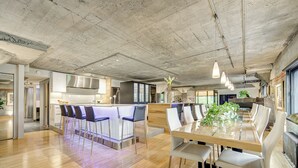 Une cuisine spacieuse dotée d’un îlot central, de tabourets de bar et d’un coin repas avec une longue table et des chaises.