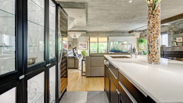 Une cuisine moderne dotée d’un grand îlot central, de meubles avec des portes en verre et offrant une vue sur l’espace de vie.