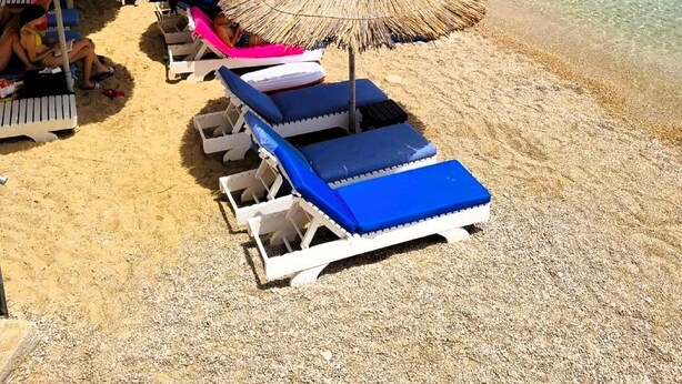 A beach with sun loungers and thatched umbrellas, a clear blue sea, and boats in the background. - Blue Charm Mobile Home (Orebic)