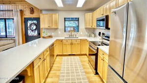 A modern kitchen with wooden cabinets, stainless steel appliances, and a large window. -  Quiet Mountain Cabin Getaway (Pinetop)