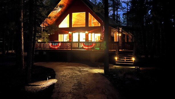 A log cabin with a large front porch, multiple windows, and a flag. -  Quiet Mountain Cabin Getaway (Pinetop)