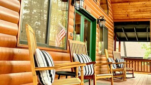 A wooden cabin with rocking chairs on a porch, large windows, and a covered area. -  Quiet Mountain Cabin Getaway (Pinetop)