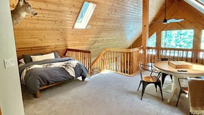A log cabin bedroom with a bed, a desk, and a dining table. -  Quiet Mountain Cabin Getaway (Pinetop)