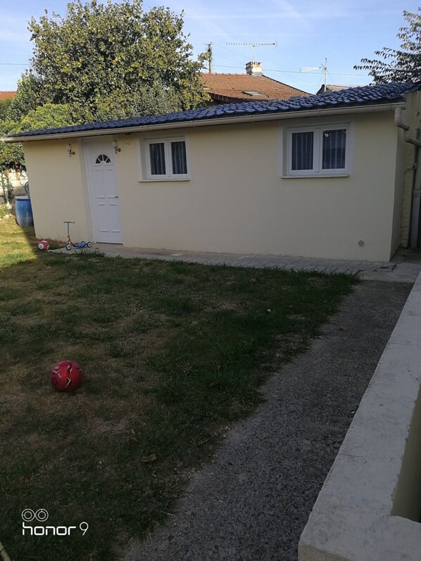 Simple, single-story building with a flat roof and a white door, offering a peaceful setting.