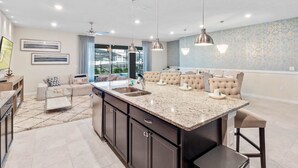A modern kitchen with a central island, pendant lighting, and a view to the living area. - Last Minute Disney! Private Pool, Hot Tub & Themed Bedrooms. Book Now! #108121 (Orlando)