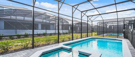 A swimming pool with a glass enclosure, surrounded by a brick patio and a greenhouse structure.