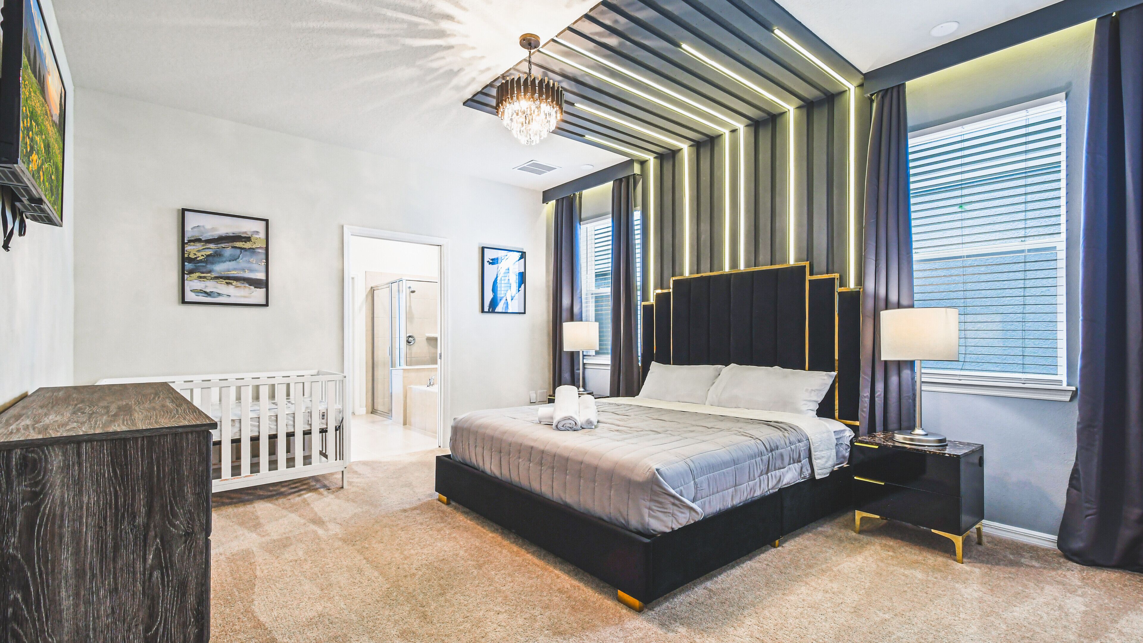 Een moderne slaapkamer met een groot bed, een nachtkastje, een ledikant en een douche.