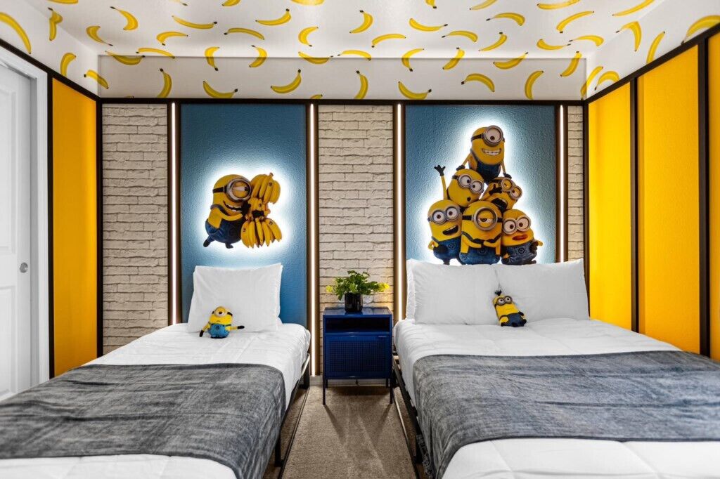 A hotel room with two beds, a brick-patterned wall, and a ceiling with banana patterns.