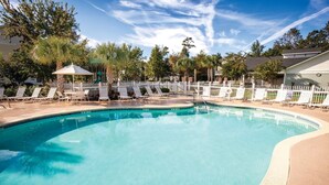 Una piscina cristalina con sillas de descanso y una cerca blanca alrededor.