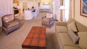 Amplia sala de estar con sofá, sillones, una mesa de centro y comedor con mesa y sillas.