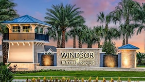 A resort sign with "Windsor Island Resort" written on it, surrounded by palm trees and a well-maintained lawn.
