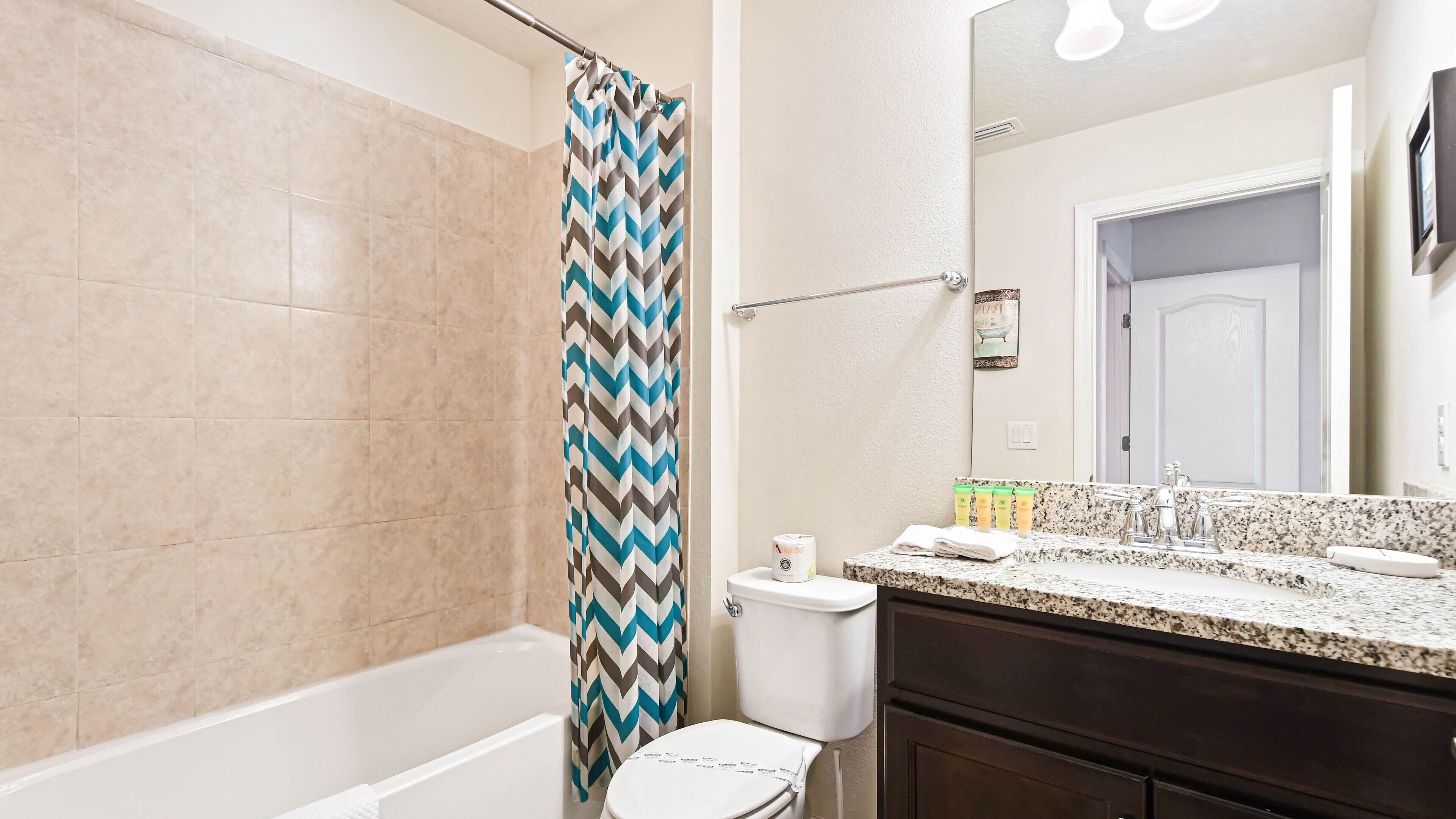 A bathroom with a shower, toilet, and vanity with a mirror.