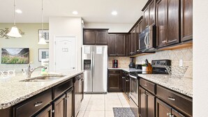 Eine moderne Küche mit Granit Arbeitsplatten, Edelstahlgeräten und dunklen Holzschränken.