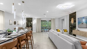 A modern dining area with a long table, chairs, and pendant lighting. - Last Minute Disney Getaway! Villa with Private Pool & Hot Tub. Book Now! #114161 (Orlando)