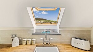 Een keuken met dakraam, waterkoker, broodrooster en spoelbak.